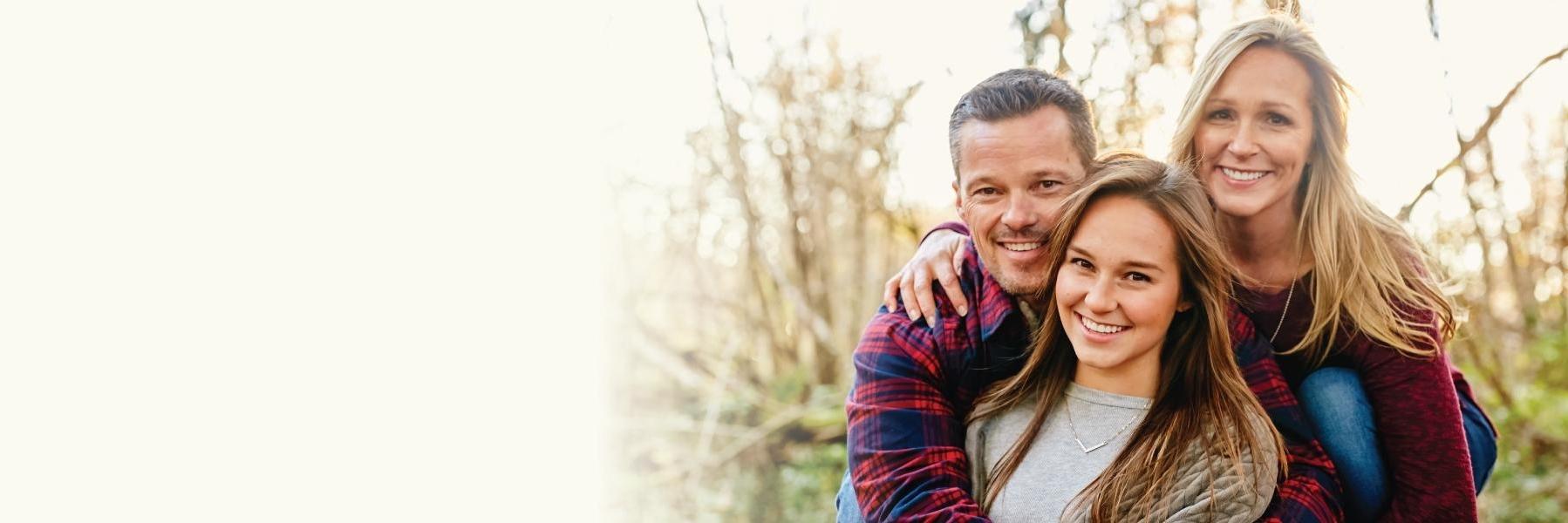 Family hugging & smiling after getting dental implants at Cook Family Dental 