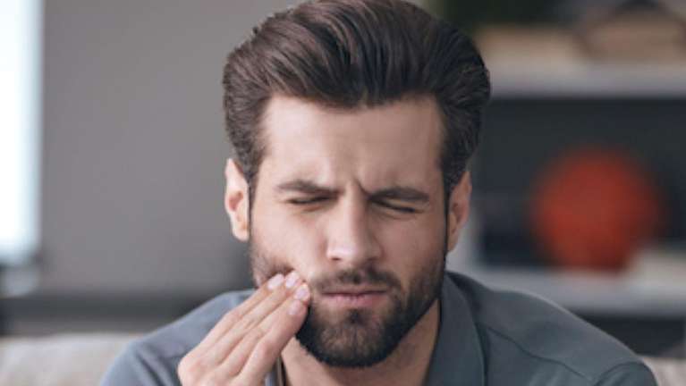 Man holding his jaw due to migraines in Birmingham, AL