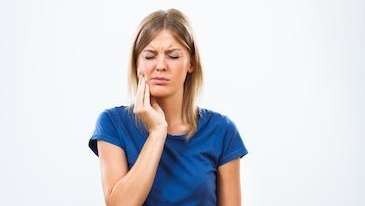 Lady holding her jaw in pain before tooth extraction at Cook Family Dental