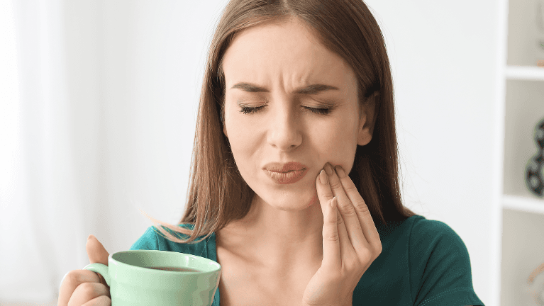 Lady holding her jaw due to pains after tooth extraction at Cook Family Dental